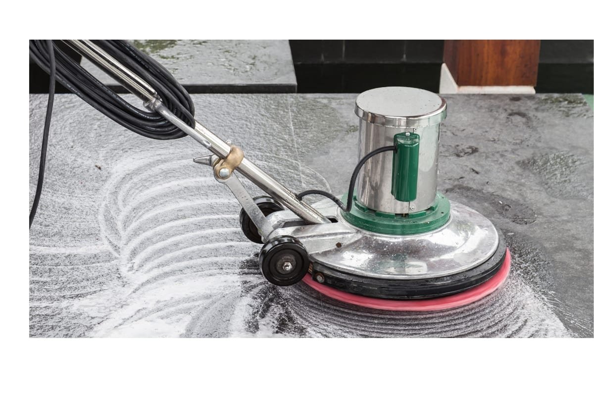 Enceradeira lavando um piso de pedra com espuma de detergente