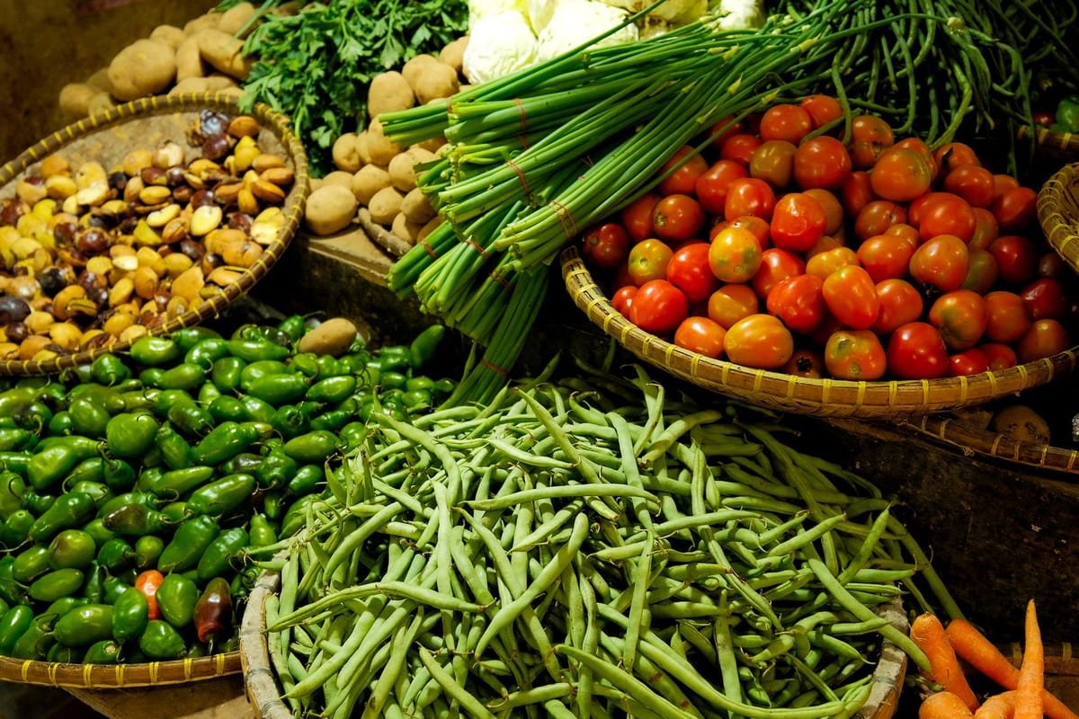 Bancas com tomates, vagens, cebolinhas e outras hortaliças frescas